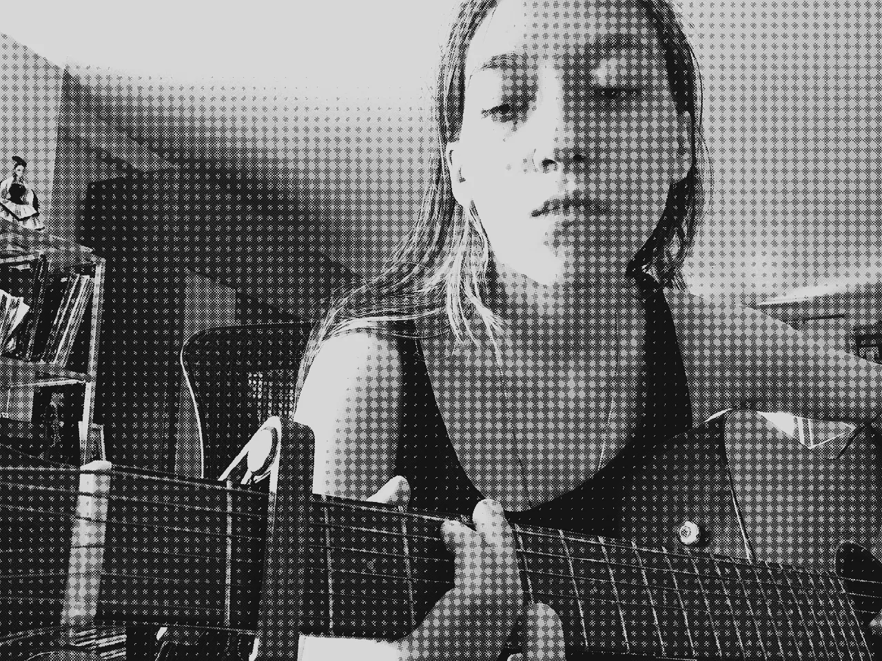 a photo of me playing guitar with a sort of bored but thoughtful expression on my face. the image is edited to have half tones and noise, and is black and white